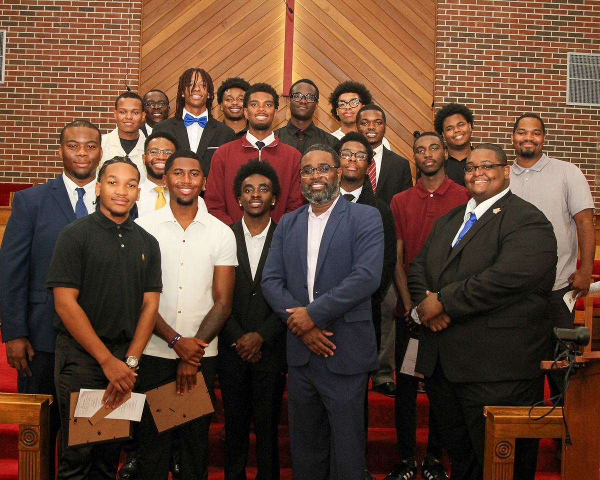 A large group of young men gathered in a sanctuary for a scholarship recognition ceremony